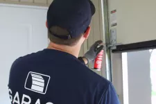 Un technicien certifié en train de lubrifier les roulettes d'une porte de garage